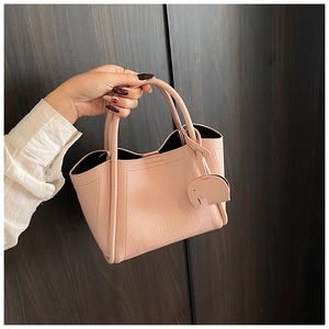 Close-up of pink litchi grain bucket bag with cute elephant charm and sturdy handles