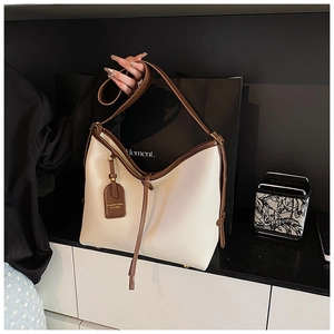 Gros plan du sac cabas en cuir grainé beige avec bordure marron et pieds en métal