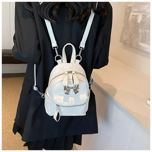 Vue détaillée d'un mini sac à dos en cuir blanc avec nœud argenté sur un mannequin