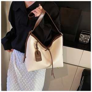 Gros plan d'un sac cabas en cuir crème avec bordure marron et clous de fond dorés