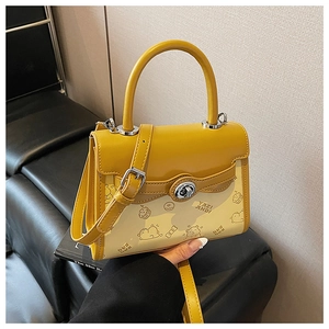 Dettaglio borsa gialla patchwork con stampe di orsi e chiusura girevole argento sul divano