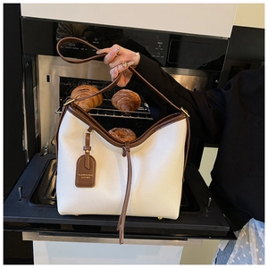 Détails du cuir litchi blanc avec bordure marron et clous de fond dorés sur le sac fourre-tout