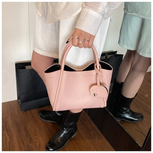 Detail view of pink lychee textured leather bucket bag with wave edge and pendant