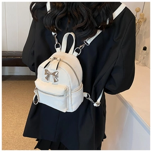 Détail du mini sac à dos blanc avec nœud en métal argenté et texture en cuir PU poli