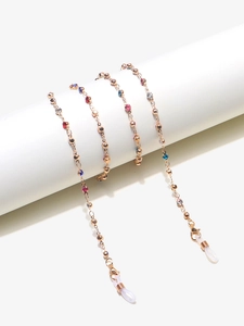 Detail of rose gold eyewear chain with colorful rhinestones on a white display stand