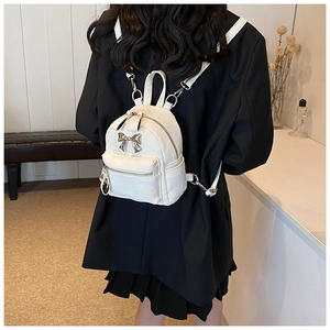 Vue de dos d'un mini sac à dos blanc avec nœud argenté porté par un mannequin