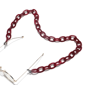 Close-up of burgundy acrylic chunky link chain attached to gold glasses on white background