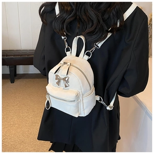 Vue arrière d'un mannequin portant un mini sac à dos blanc avec nœud argenté sur une veste