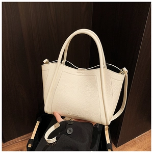 Close-up of cream leather bucket bag texture with engraved logo and adjustable strap