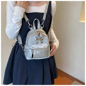 Vue détaillée d'un mini sac à dos en velours avec nœud en métal argenté et zip