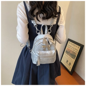 Détail d'un mini sac à dos en velours gris argenté avec un nœud métallique sur mannequin