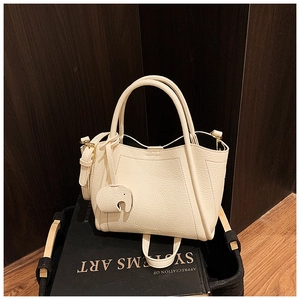 Close-up of creamy white bucket bag in lychee texture with a cute elephant charm