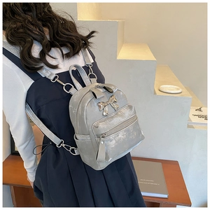 Détail d'un mini sac à dos gris argenté à effet métallisé avec boucle en nœud