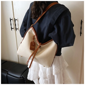 Vue détaillée du grand sac cabas crème avec anses marron porté à l'épaule d'un mannequin