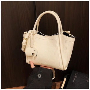 Close-up of off-white lychee grain leather bucket bag with cute elephant charm detail