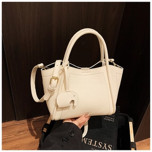 Detail of cream lychee leather bucket bag featuring a cute elephant charm and handles