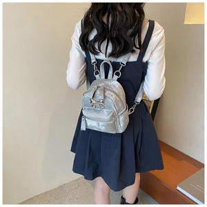 Vue arrière d'un mini sac à dos argenté métallisé avec détail de nœud sur modèle