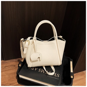 Detail of cream leather bucket bag with litchi texture and cute elephant charm