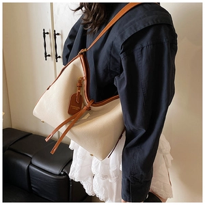 Détail du sac cabas blanc cassé à grain de litchi avec bords bruns et étiquette en cuir