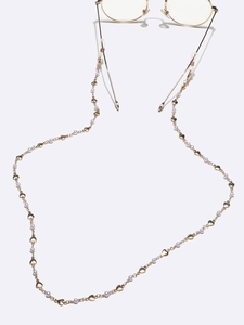 Detail van de gouden brillenketting met gepolijste hartjes en witte kunstparels