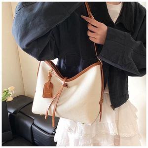 Détail du cabas blanc crème à grain de galet avec bords marron et étiquette en cuir chic