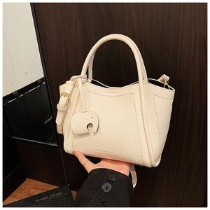 Close-up of cream lychee texture leather bucket bag with cute elephant charm detail