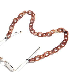 Macro detail of amber marble resin chain links with non-slip rubber loop for eyewear