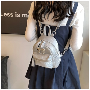 Mini sac à dos argenté avec nœud porté par un mannequin dans un cadre moderne