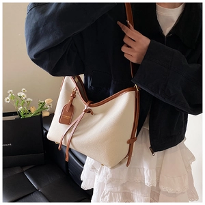 Détail du grand sac cabas crème avec motif litchi et bordures marron sur un modèle