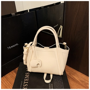 Close-up of off-white lychee grain leather bucket bag with cute elephant charm and strap