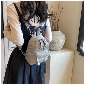 Vue arrière d'un mini sac à dos gris avec boucle nœud doré sur fond minimaliste