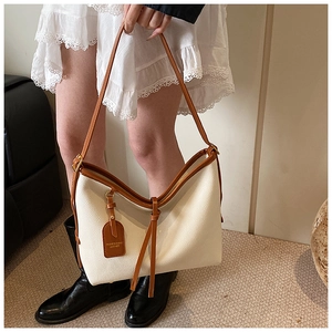Détail du sac cabas crème avec poignées en cuir marron et texture grainée
