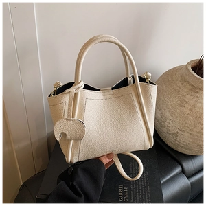 Close-up of cream pebble leather bucket bag with top handles and elephant charm