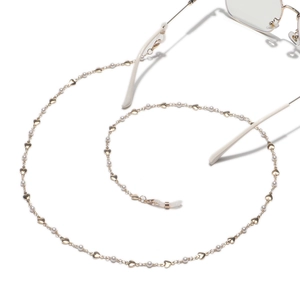 Handgemaakte gouden brillenketting met witte parels en hartjes op witte achtergrond