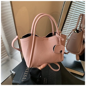 Detail of pink lychee grain leather bucket bag featuring a cute elephant charm