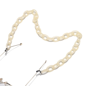 Detail of cream white acrylic eyeglass chain with golden metal links and rubber ends