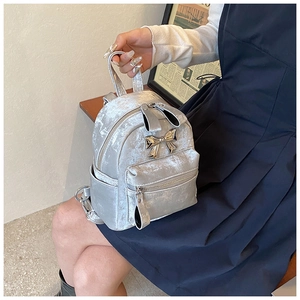 Détail d'un mini sac à dos en velours argenté avec nœud métallique et fermeture oreilles de lapin