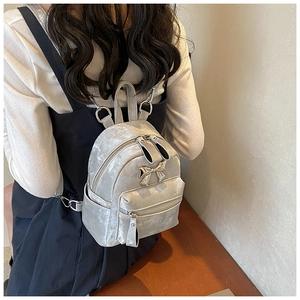 Détail d'un mini sac à dos en velours gris argenté avec nœud métallique et poche zippée