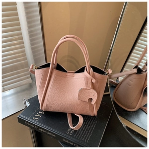 Detail of pink lychee leather bucket bag with cute elephant charm and artistic backdrop
