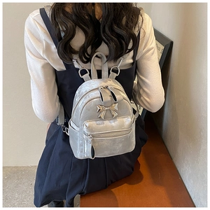 Détail d'un mini sac à dos en velours argenté avec nœud métallique sur le modèle