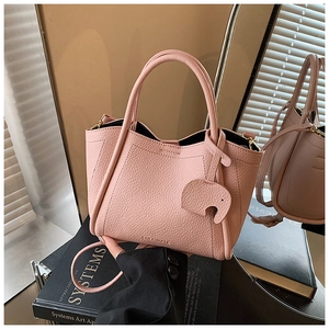 Detail of pink pebbled leather tote bag with elephant charm and gold hardware accents
