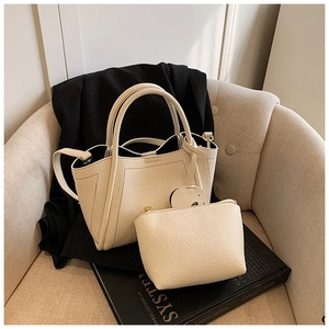 Detail of cream white lychee grain leather tote bag set on a chair with black blazer