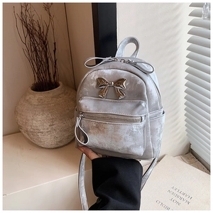 Gros plan détaillé d'un mini sac à dos gris avec nœud métallique argenté et texture en cuir PU