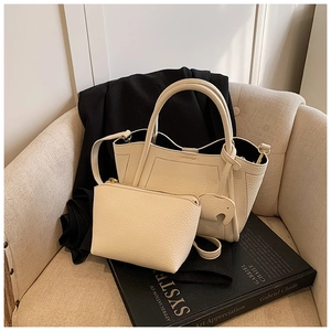 Close-up of cream-white bucket bag set with pebble leather texture and side tassel charm