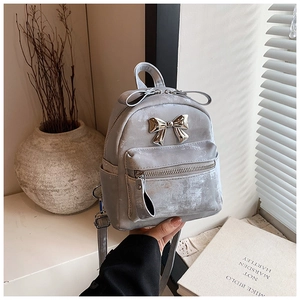 Détail d'un mini sac à dos gris avec nœud métallique argenté et poche à fermeture éclair