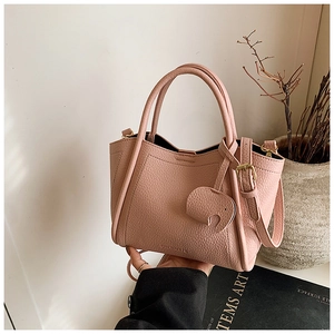 Close-up of pink lychee grain leather bucket bag with cute elephant charm and round handles