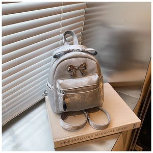 Gros plan détaillé d'un mini sac à dos argenté pailleté avec des nœuds métalliques chic