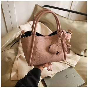 Close-up of pink litchi grain leather bucket bag with cute elephant charm and gold hardware