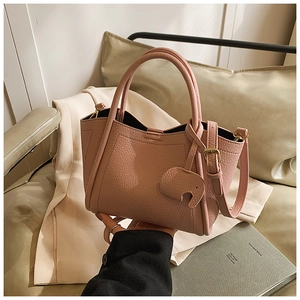 Detail of pink pebbled leather bucket bag with cute elephant charm and round handles