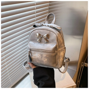 Détail d'un mini sac à dos argenté métallisé avec texture craquelée et nœud décoratif